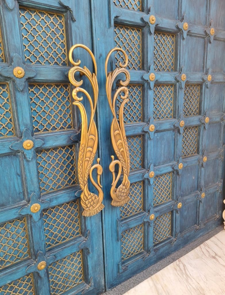 Pilibhit House- a massive wooden gate in blue with gold trappings reminiscent of medieval majesty 