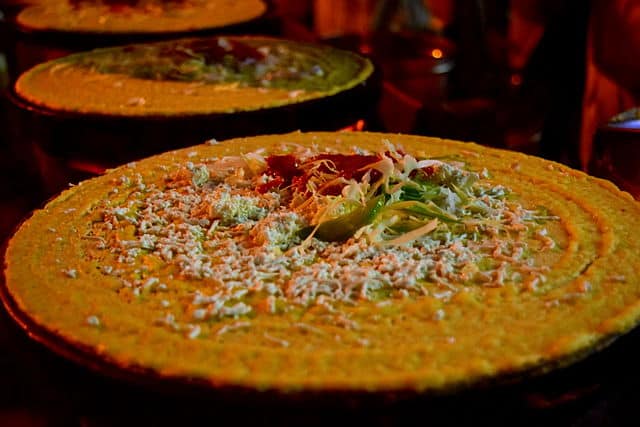 The dosa bar at a 2025 wedding is where tradition turns theatrical, guests customise fillings like truffle cheese and masala corn, while chefs craft each dosa live. It’s crispy, curated, and the hottest spot at the celebration, literally and socially. Courtesy: Wikimedia