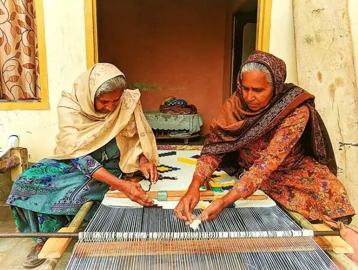 Two skilled women hand-weaving a traditional dhurrie on a loom, preserving generations of craft and culture in rural India. Courtesy: ciceroni.in